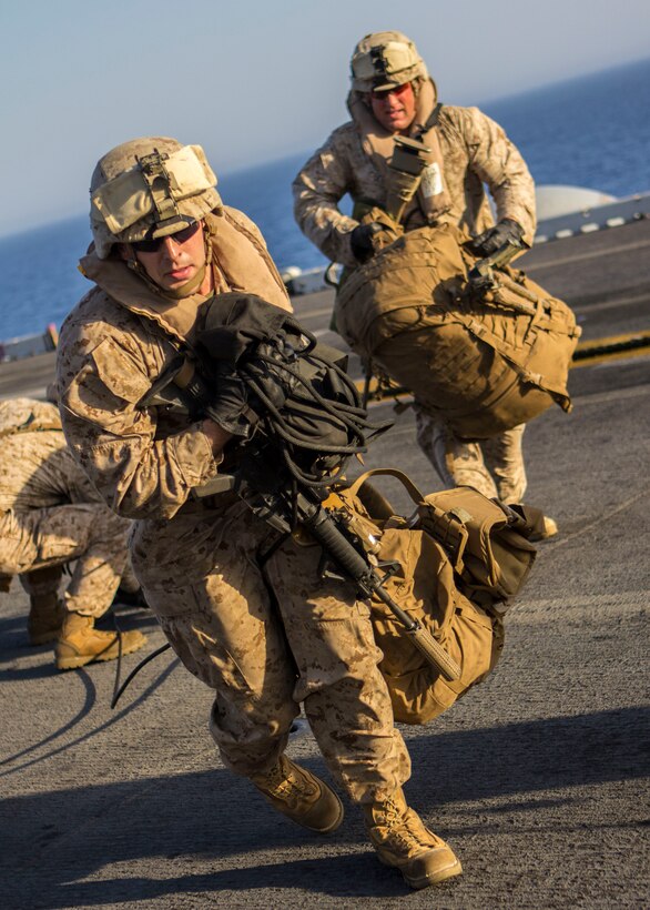 U.S. Marines assigned to Battalion Landing Team 3/2, 26th Marine Expeditionary Unit (MEU), carry gear after fast roping from a CH-53E Super Stallion assigned to Marine Medium Tiltrotor Squadron (VMM) 266 (Reinforced), 26th MEU, during familiarization training on the flight deck of the USS Kearsarge (LHD 3), at sea, June 30, 2013. The 26th MEU is a Marine Air-Ground Task Force forward-deployed to the U.S. 5th Fleet area of responsibility aboard the Kearsarge Amphibious Ready Group serving as a sea-based, expeditionary crisis response force capable of conducting amphibious operations across the full range of military operations. (U.S. Marine Corps photograph by Sgt. Christopher Q. Stone, 26th MEU Combat Camera/Released)