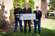Recruiting Substation Mankato's Sgt. Jared Johnson and Capt. Jackie Jaspers present Nicholas Herwig with an NROTC Scholarship at Mankato West High School May 23. General Motors CEO Daniel Akerson, a Naval Academy graduate and Mankato West 1966 alumnus, served as the guest speaker at the school's awards ceremony.