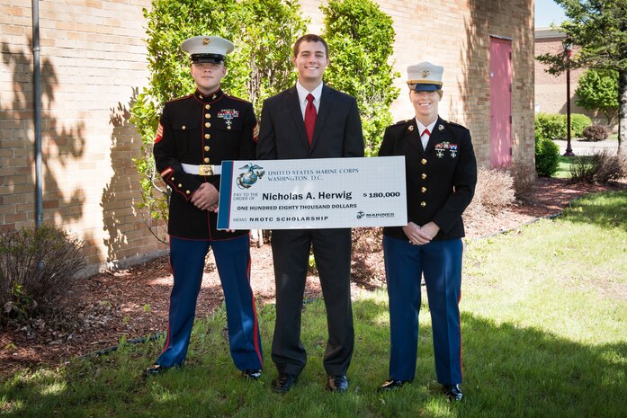 Recruiting Substation Mankato's Sgt. Jared Johnson and Capt. Jackie Jaspers present Nicholas Herwig with an NROTC Scholarship at Mankato West High School May 23. General Motors CEO Daniel Akerson, a Naval Academy graduate and Mankato West 1966 alumnus, served as the guest speaker at the school's awards ceremony.