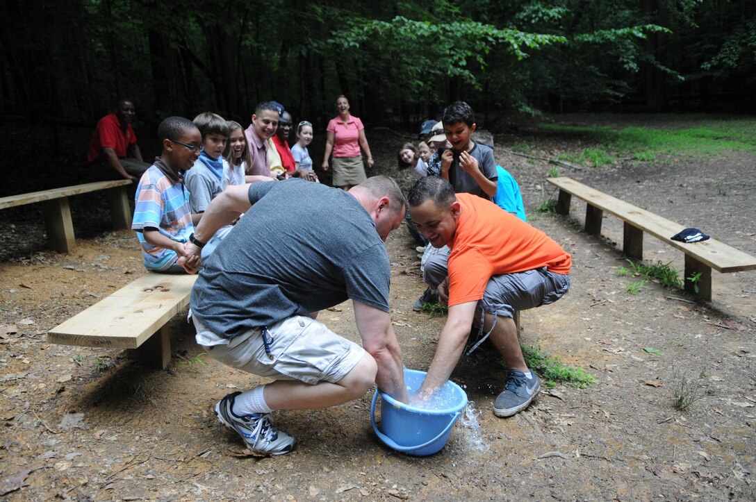 Cmdr. Chris Niles, left, and Sgt. Kris Atkinson battle for the bar of soap floating in a bucket during a game of “Electricity” at the “Tune In with Dad” father and child event organized by Quantico’s Family Advocacy Program at Prince William National Forest on June 28, 2013.