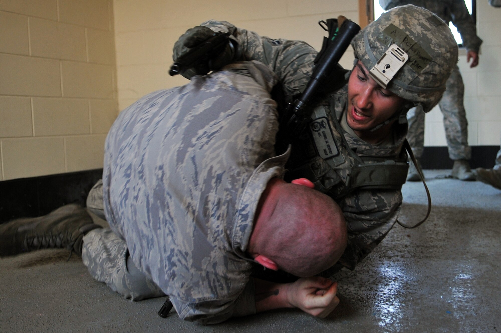 Airman 1st Class Daniel Rashef, 51st Security Forces Squadron Quick Reaction Team leader, wrestles Staff Sgt. Ryan Friend, 51st SFS defender acting as a role player, in a barricaded hostage scenario during a joint QRT training exercise at Osan Air Base, Republic of Korea, June 29, 2013. The QRT is a specialized group of security forces members that trains with other Osan emergency responders, including medics, fire fighters, and explosive ordnance disposal members. This exercise, along with future exercises, is designed to facilitate joint emergency response training to gain a better understanding of each emergency responder’s role at the tactical level during high-risk responses.  (U.S. Air Force photo/Senior Airman Alexis Siekert)