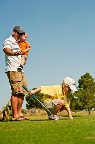 U.S. Air Force Maj. Travis Clegg, 64th Aggressor Squadron pilot, holds his son, Boston, while congratulating his daughter, Madison, after she sank a putt during the annual Sunrise Vista Junior Kids Golf Clinic June 28, 2013, at Nellis Air Force Base, Nev. The clinic taught children the basic fundamentals of golf. (U.S. Air Force photo by Senior Airman Daniel Hughes)