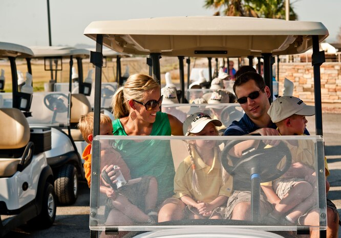 Jennifer Clegg, wife of U.S. Air Force Maj. Travis Clegg, 64th Aggressor Squadron pilot, holds her son, Boston, as they sit in a golf cart with her other children Madison, Noah and their uncle Danny Wright, during the annual Sunrise Vista Junior Kids Golf Clinic June 28, 2013, at Nellis Air Force Base, Nev. Families were invited to come out and participate in a par 3 scramble match with the children. (U.S. Air Force photo by Senior Airman Daniel Hughes)
