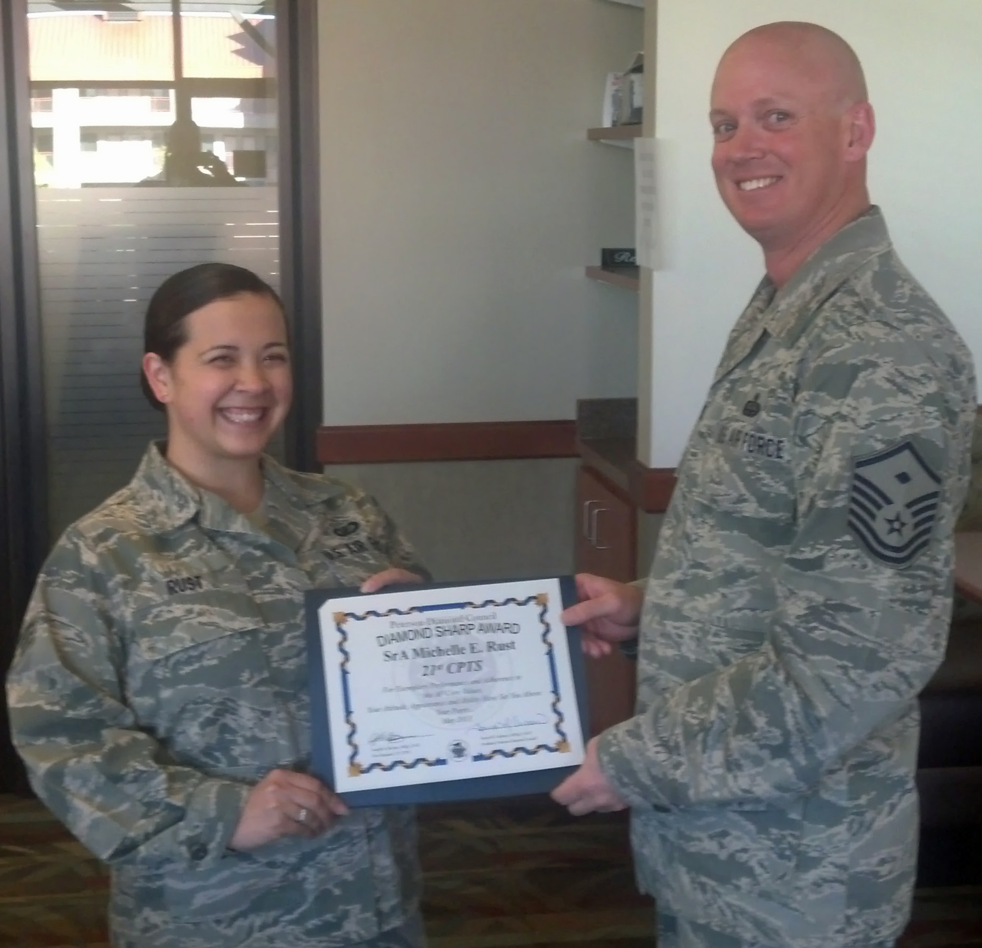 PETERSON AIR FORCE BASE, Colo. -- Senior Airman Michelle Rust, 21st Comptroller Squadron military pay technician, receives the Pikes Peak Top 3 for the Diamond Sharp Award from Master Sgt. Joseph Beymer, 21st Comptroller Squadron first sergeant. The award recognizes Airmen who go beyond their everyday tasks and demonstrate a high level of excellence, specifically in customer service and professional appearance. Any first sergeant or senior NCO serving as a first sergeant who observes outstanding performance may nominate someone for the award to the first sergeants' council. (U.S. Air Force photo)