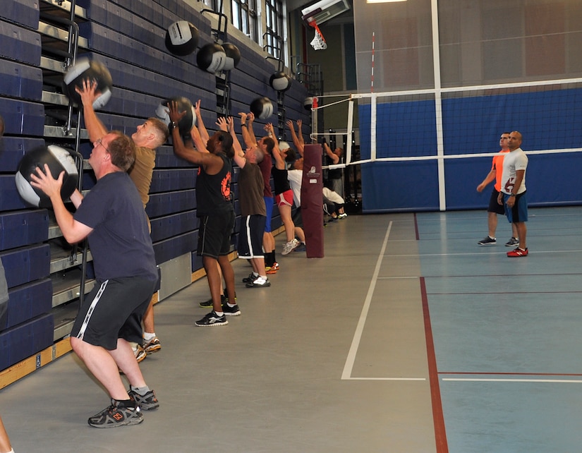 Functional Fitness Program students perform a wall-ball skill during the Functional Fitness Program, while instructors U.S. Marine Corps Gunnery Sgt. Juan C. Ospina and U.S. Army 1st Lt. John Lambertson watch for correct form at the Anderson Field House on Fort Eustis, Va., June 19, 2013. The Functional Fitness Program “CrossFit” class normally consists of a light warm up for mobility, a gymnastic or weightlifting skill and then a full workout. (U.S. Air Force photo by Tech. Sgt. April Wickes/Released)