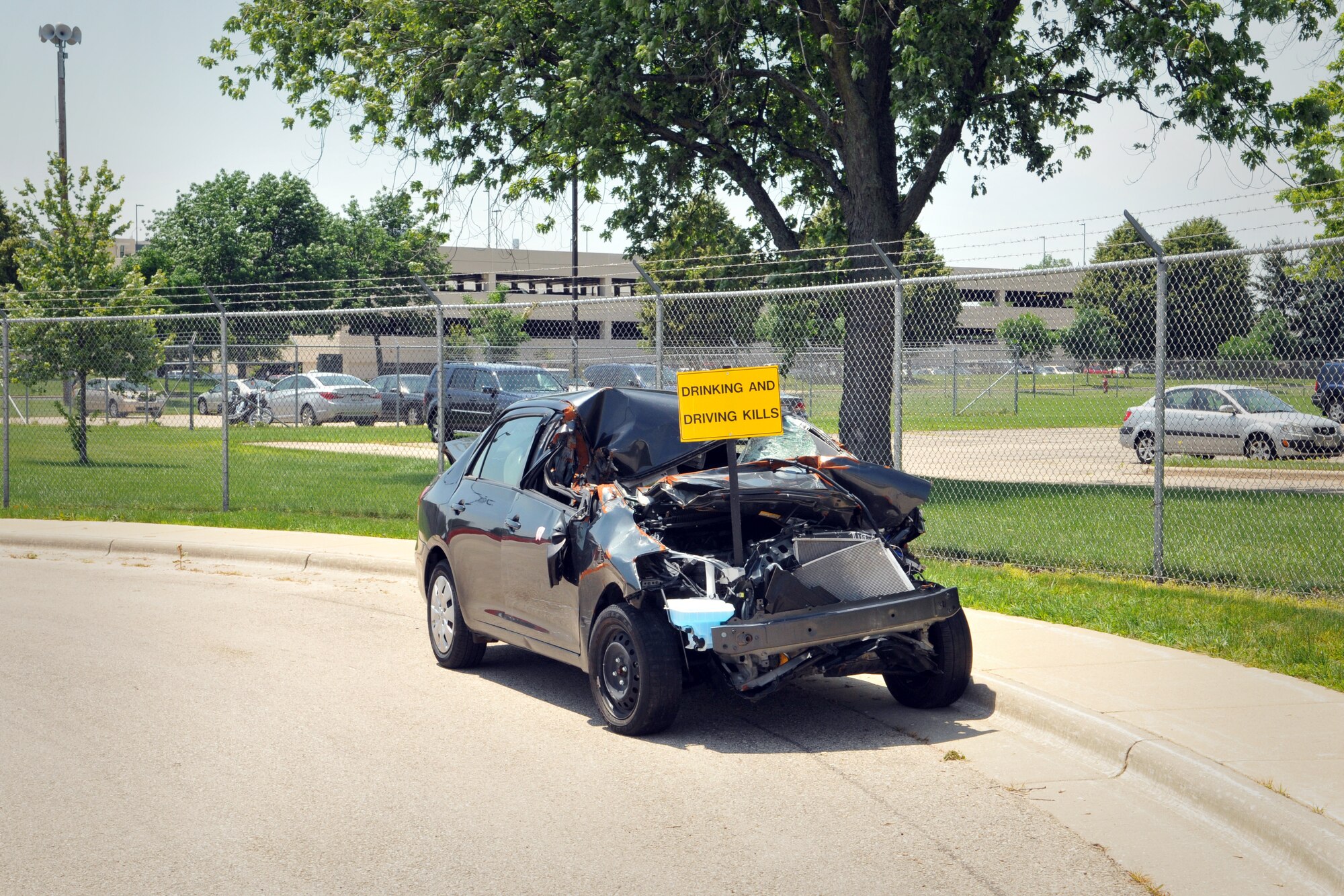A wrecked car being used to illustrate the dangers of drinking and driving sits near the main gate of Truax Field, July 1, 2013.  The car, with a bright yellow sign that reads “Drinking and Driving Kills,” was placed there to ensure anyone leaving Truax Field will have a visual reminder of the consequences that drinking and driving can have.  (National Guard photo by 1st Lt. Stephen Montgomery)