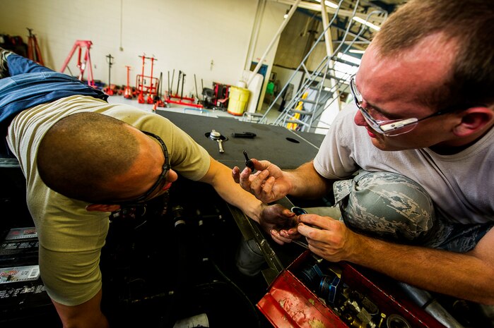 Airman 1st Class Joshua Wachtel, 628th Logistics Readiness Squadron vehicle maintenance technician, hands Senior Airman Matthew Trevino a bolt, June 25, 2013, at Joint Base Charleston – Air Base, S.C. Vehicle maintenance technicians maintain JB Charleston's entire vehicle fleet, keeping cars, trucks and buses operating smoothly. (U.S. Air Force photo/ Senior Airman George Goslin)