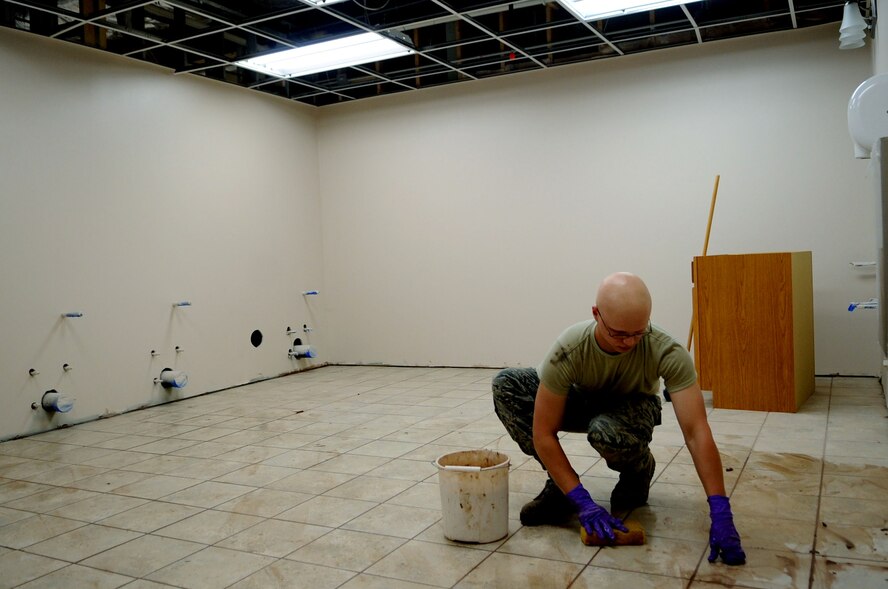 Airman 1st Class Michael Hoersten, 319th Civil Engineer Squadron, grouts tile in a newly refurbished restroom in Building 408 on Grand Forks Air Force Base, N.D. Airmen from the 319th CES are renovating a portion of the building as part of a Contingency Construction Home Station Training (CCHST) project, which serves as in-house training to hone engineers’ skills in their respective vocations, as well as improve quality of life for building occupants. (U.S. Air Force photo/Staff Sgt. Amanda Grabiec)