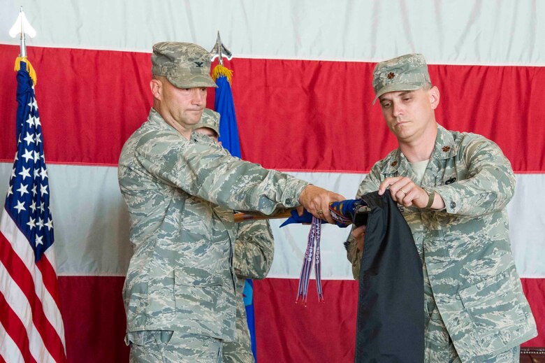 From left, Col. Dane P. West, 388th Maintenance Group commander, and Maj. Jason J. Ross, 388th Maintenance Operation Squadron commander, furl the squadron's guidon during a deactivation ceremony at Hill Air Force Base, Utah, June 28, 2013. The 388th MOS deactivated as part of an Air Force wide restructuring initiative to better allocate company and field grade officers to needed positions. (U.S. Air Force photo by Airman 1st Class Tiffany J. DeNault/Released)