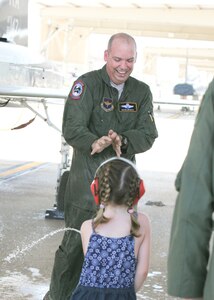 Natalie sprays her dad, Col. David Drichta, 12th Operations Group deputy commander, with water from a fire extinguisher after his first flight back after his battle with cancer at Joint Base San Antonio-Randolph, Texas June 19, 2013.  Drichta was diagnosed with Stage IV cancer in February 2012 and, after more than a year in recovery, was medically cleared to return to flight status.  The flight marked his return to flight status as well as his 3,000th flight hour in Air Force aircraft. (Courtesy photo by Stacy Nyikos)