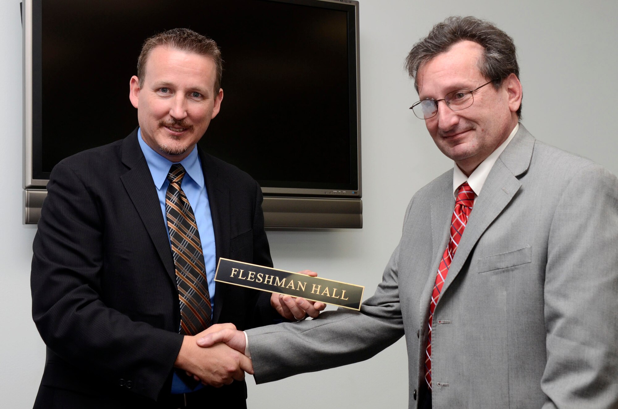 Lloyd F. Clark, special agent with the Air Force Office of Special Investigation presents former counter-terrorism OSI agent Jeff Fleshman with the name plate that will be placed in the hall dedicated in his name at a ceremony held on Dobbins Air Reserve Base, Ga. June 27. Fleshman was instrumental in the OSI relocation to their current facility. (U.S. Air Force photo/Don Peek)