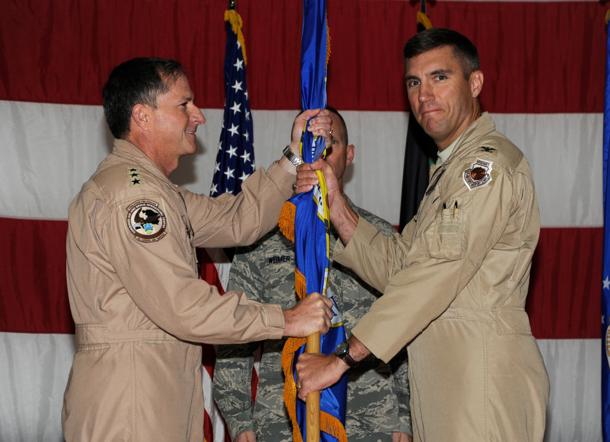 Lieutenant Gen. David L. Goldfein, Commander, U.S. Air Forces Central, left, passes the 386th Air Expeditionary Wing guidon to Col. John M. Klein during a change of command ceremony at an undisclosed location in Southwest Asia July 1, 2013. Klein assumed command of the 386th AEW from Col. David S. Farrow. (U.S. Air Force photo by Master Sgt. Christopher A. Campbell)