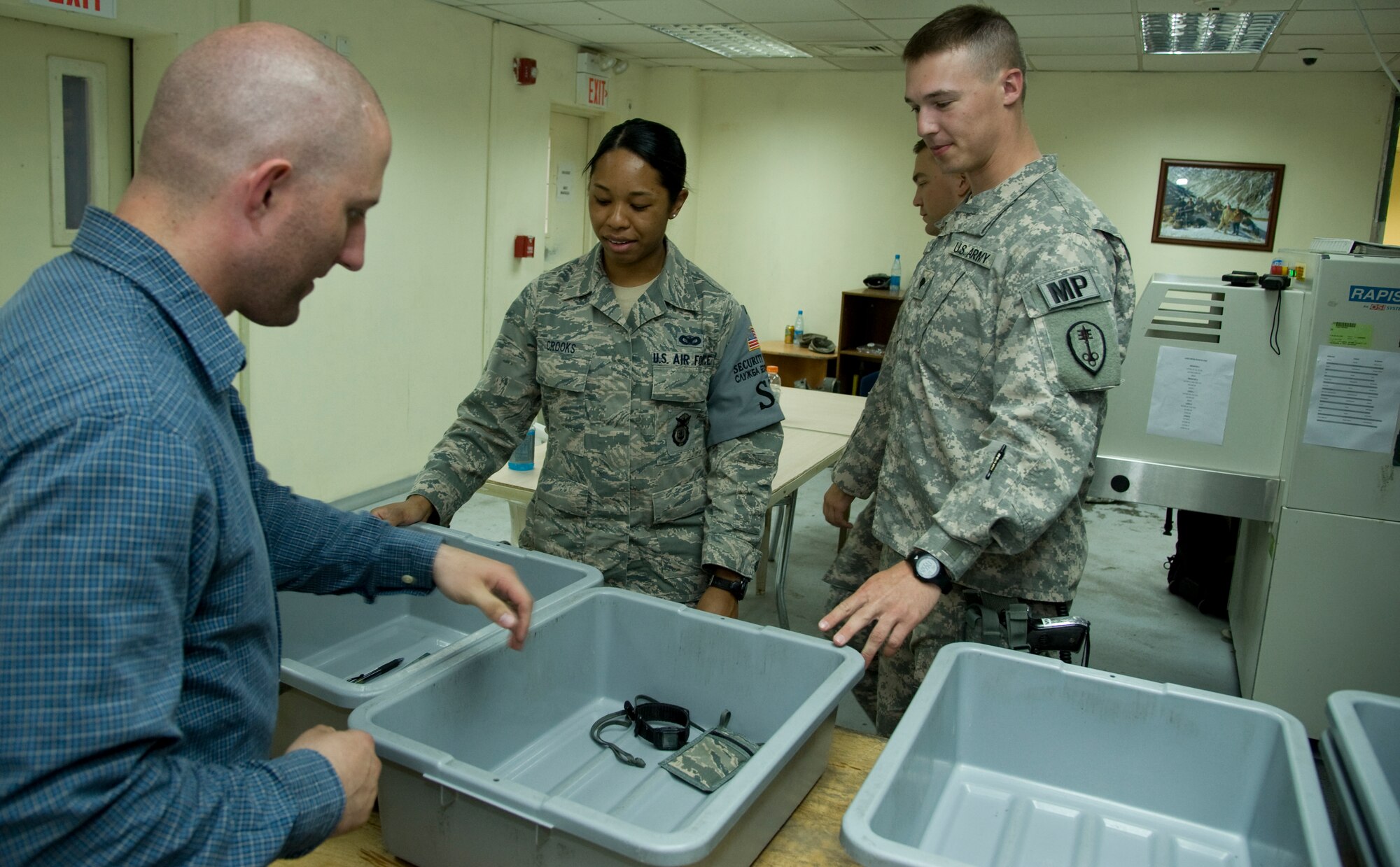 U.S. Air Force Senior Airman Tanya Crooks, 376th Expeditionary Security Forces Squadron, center, and U.S. Army Spc. Stephen Resch, 391st Military Police Battalion, Detachment 5, examine belongings of a service member as he enters the Transit Center Access Point at Transit Center at Manas, Kyrgyzstan, June 27, 2013. The new initiative of Air Force and Army service members working together to secure the front gate was created to make up for a decrease in manning from Airmen leaving on forward missions and job reassignments. (U.S. Air Force photo/Staff Sgt. Krystie Martinez)