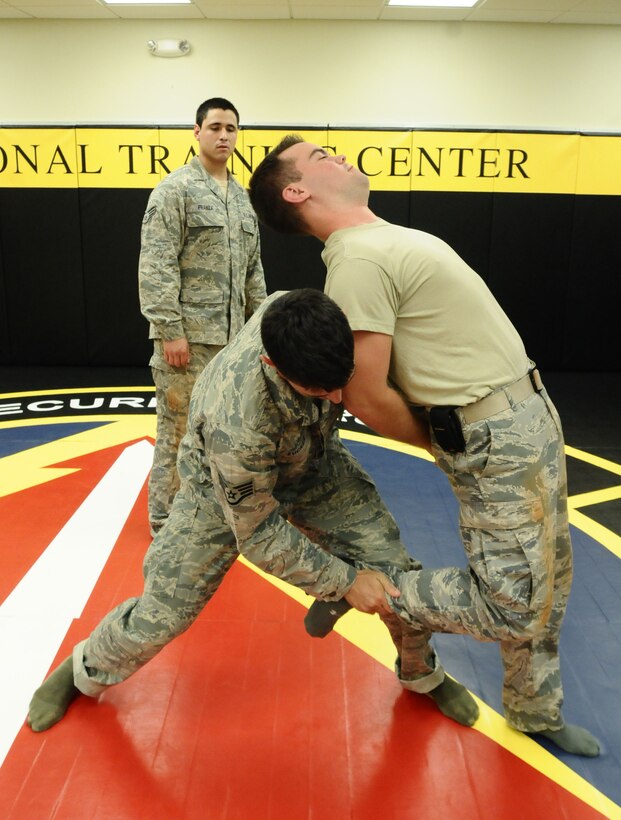 Staff Sgt. Jake Zucker (center), 736th Security Forces Squadron Pacific Regional Training Center instructor, demonstrates a takedown maneuver during the search and handcuffing portion of a combatives course at the Pacific Regional Training Center on Northwest Field, Guam, June 26, 2013. The training was part of a new sustainment training program that will become part of a monthly regimen designed to keep Airmen current on skills such as rules of engagement, use of force, integrated defense and rifle-fighting techniques. (U.S. Air Force photo by Airman 1st Class Mariah Haddenham/Released)