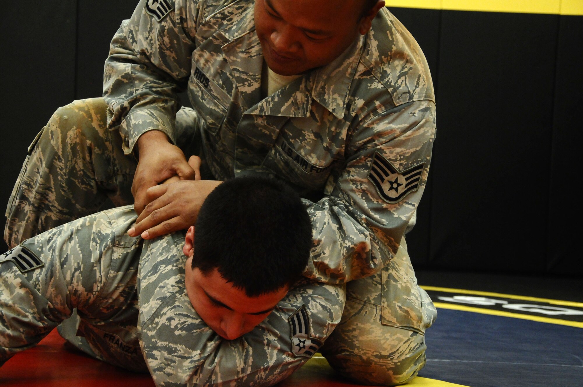 Senior Airman Daniel Franza, 36th Contingency Response Group personnel journeyman, practices a choke hold on Staff Sgt. John Rios, 36th Mobility Response Squadron aerial porter, during a combatives training scenario at the Pacific Regional Training Center on Northwest Field, Guam, June 26, 2013. The training was part of a new sustainment training program that will become part of a monthly regimen designed to keep Airmen current on skills such as rules of engagement, use of force, integrated defense and rifle-fighting techniques. (U.S. Air Force photo by Airman 1st Class Mariah Haddenham/Released)