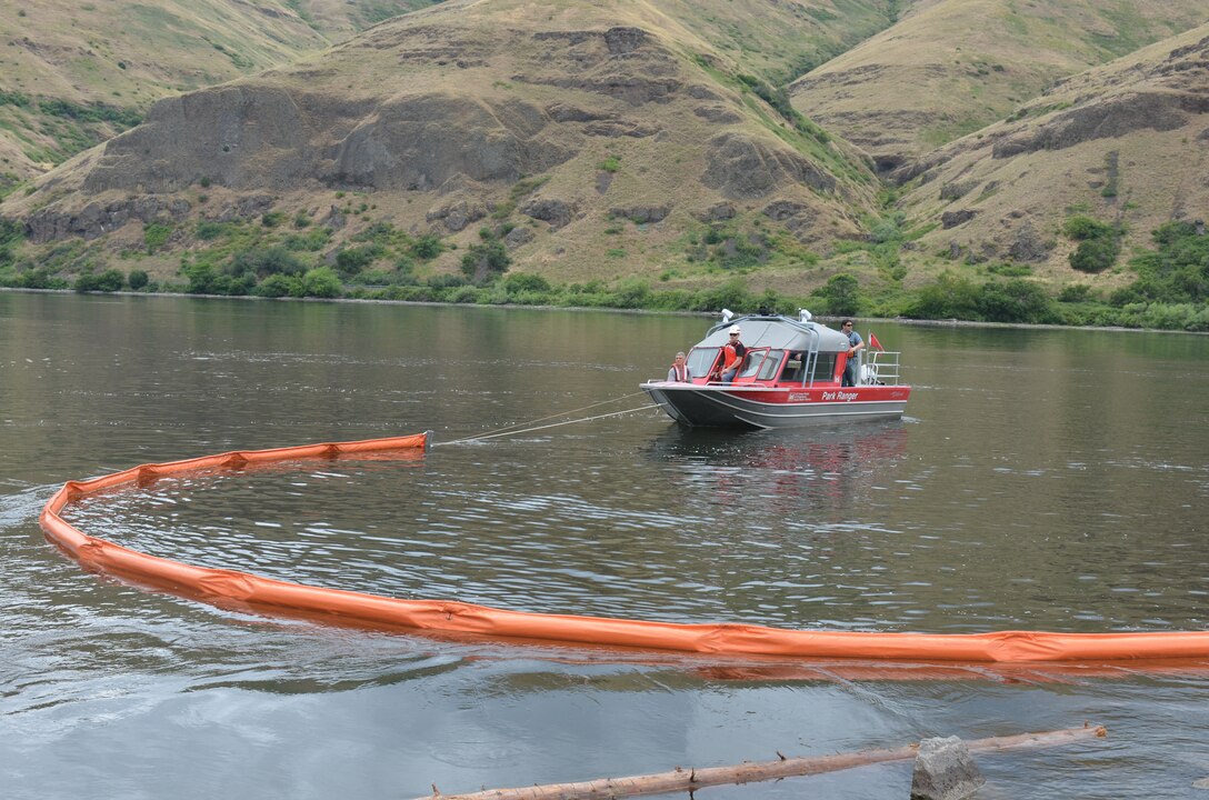 A Corps Park Ranger boat and crew deploy an oil containment boom. 