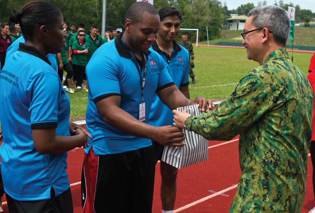 U.S. Navy Petty Officer 2nd Class Victor S. Parker, center, accepts a gift from Royal Brunei Armed Forces Lt. Col. Mohd Hafizul Hassan, right, on behalf of his team after placing second in a tug-of-war competition during a sports field meet June 14 at Berakas Army Garrison Camp, Brunei. The competition took place during ADMM-Plus AHMX. Parker is a hospital corpsman with Naval Environmental Preventive Medicine Unit 6. Hassan was the chief medical officer for the exercise. 