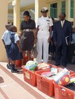Two Bahamian students greet U.S. Ambassador Nicole Avant, Navy Lt. Cmdr. Janice Smith and Howard Newbold, District Superintendent for the North Western District, on arrival at Woodcock Primary School Sept. 9. U.S. Northern Command funded $6,000 in school supplies for local schools as part of its longstanding partnership with the people of The Bahamas and demonstrates the Department of Defense’s commitment to helping to strengthen communities and build partnerships around the world.
       