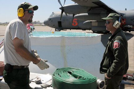 Aircrews from the 146th Air Expeditionary Group (part of a unified military support effort of U.S. Northern Command to provide assistance to the U.S. Forest Service, state and local agencies, and the National Interagency Fire Center in battling large, uncontrolled wildfires throughout the nation) work with Air traffic controllers, lead pilots and maintenance crews to deliver retardant to fire-damaged areas.  Here, Forest Service workers look on as aircraft MAFFS five parks for servicing and reload in Greenville, SC.