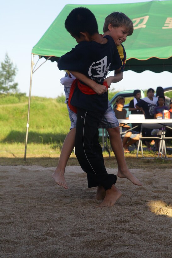 Preston D. Flinders, rear, battles his wrestling opponent June 22 at Mae-no-hama Field during his second match in the Henoko Okinawa-Style Sumo Tournament. The objective of Okinawa-style sumo is to get the opponent on their back without the participants letting go of each other’s belts or using any kind of striking technique. Differing from Japanese sumo, Okinawa sumo closely resembles grappling and includes traditional martial arts attire, called a gi. Flinders is the 10-year-old son of Capt. Thomas S. Flinders, a logistics officer with Headquarters Battery, 12th Marine Regiment, 3rd Marine Division, III Marine Expeditionary Force. (U.S. Marine Corps photo by Lance Cpl. Natalie M. Rostran/Released)
