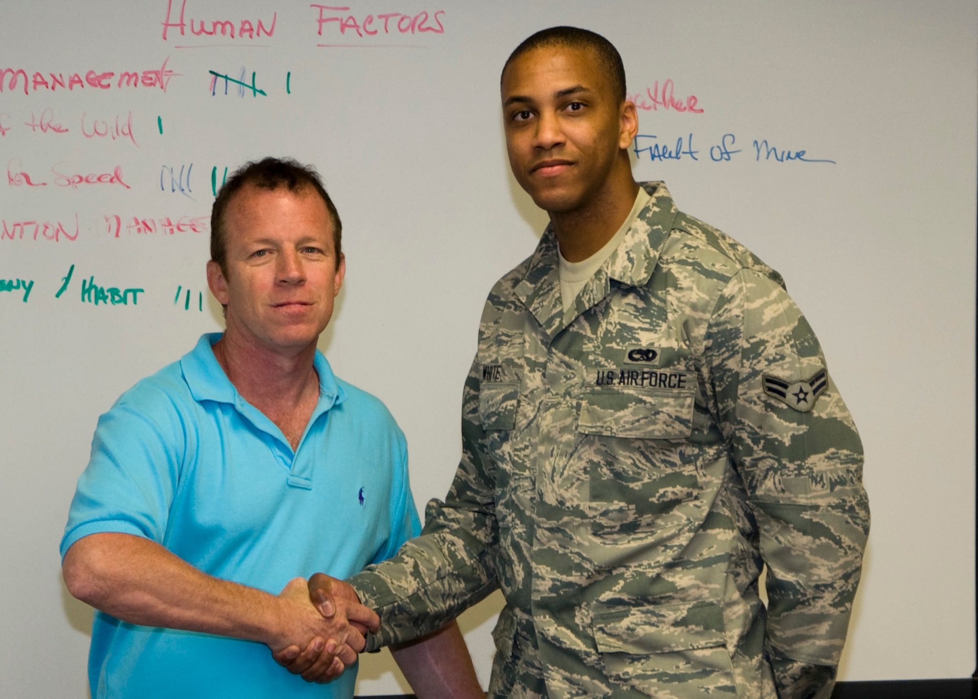 Tim Hahn, 436th Airlift Wing Safety Office occupational safety and health specialist, shakes hands with Airman 1st Class Michael White, 736th Aircraft Maintenance Squadron crew chief, after completion of Alive at 25 June 26, 2013, Dover Air Force Base, Del. White is Hahn’s 2000th graduate since the class started in 2009.(U.S. Air Force photo/Senior Airman Jared Duhon)
