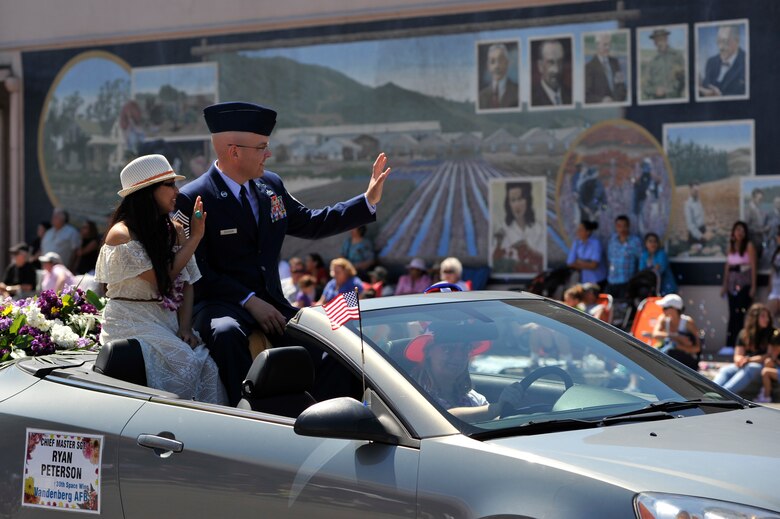 LOMPOC, Calif. -- Chief Master Sgt. Ryan Peterson, 30th Space Wing command chief, and wife Andra, wave to spectators during the city of Lompoc's 61st annual Flower Festival Parade on Saturday, July 29. Peterson rode in the procession for the parade which was themed "A Salute to the Red, White and Blue". (U.S. Air Force photo/Michael Peterson)