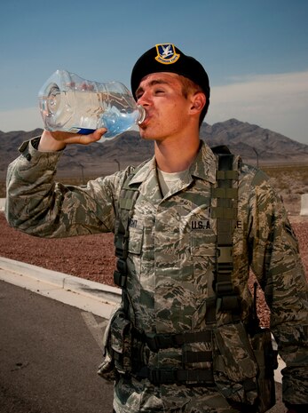 Airman 1st Class Jeffrey Albright, 99th Security Forces Squadron journeyman, drinks water in front of the Area 2 gate July 2, 2013, at Nellis Air Force Base, Nev. Working in near-record temperatures as high as 117 degrees, Airmen must hydrate frequently in order to avoid heat related injuries such as heat stroke. Additionally, work-rest cycles should also be considered. The heat wave, which includes parts of California, Nevada and Arizona, is expected to last the rest of the week. (U.S. Air Force photo by Master Sgt. Jason W. Edwards)