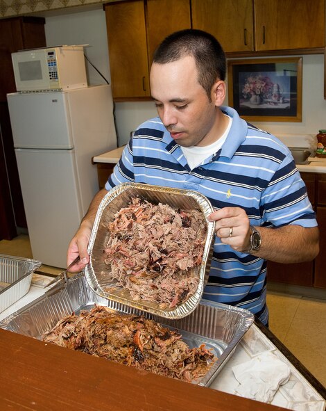 Staff Sgt. James Bray, Executive Assistant to the 436th Airlift Wing command chief, dumps pulled pork barbeque into a serving tray June 26, 2013, at the Eagle's Net Cafe on Dover Air Force Base, Del. The Wing Staff Agencies hosted a home cooked meal for dorm residents. (U.S. Air Force photo/Roland Balik)