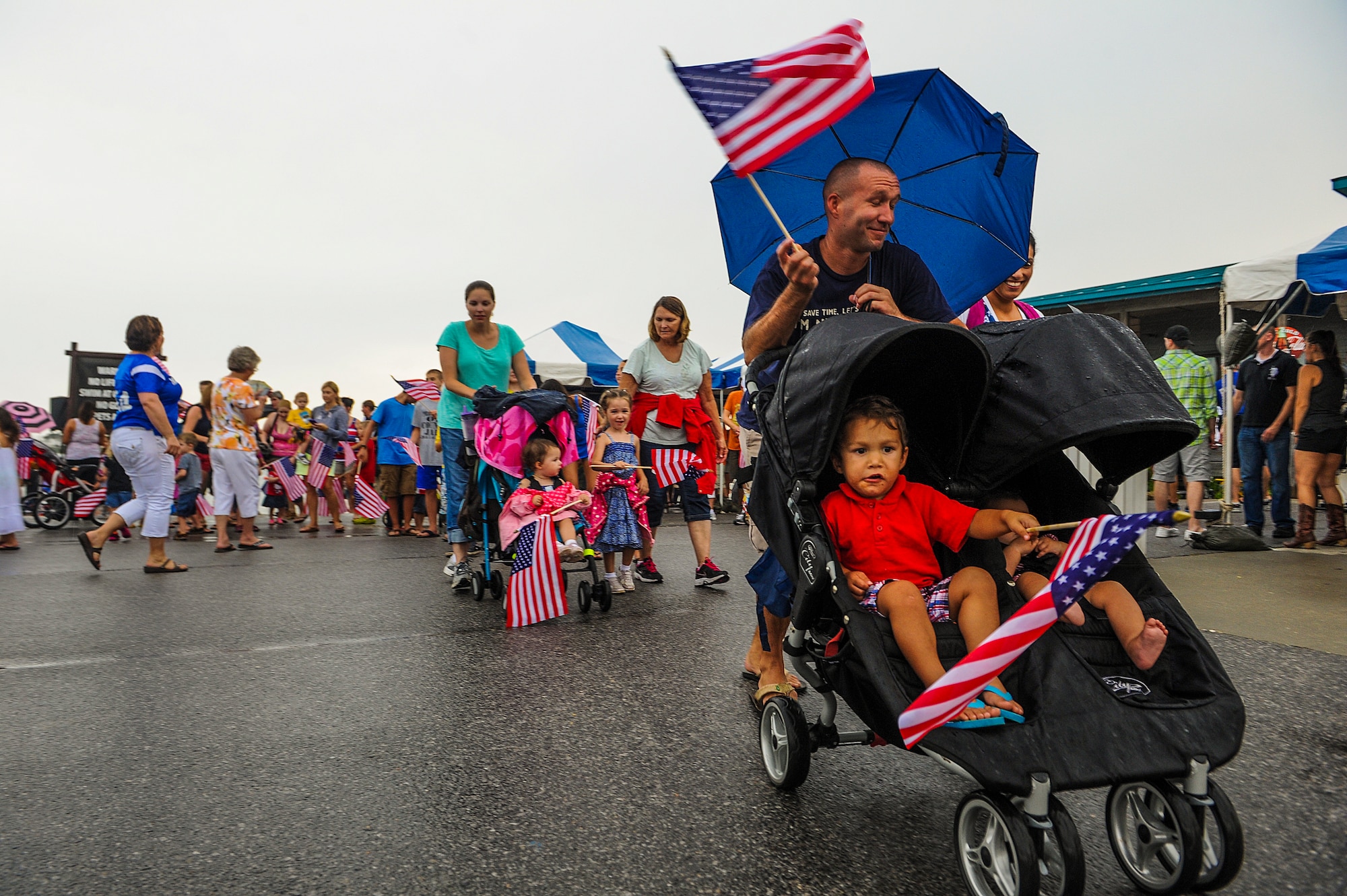 U.S. Marine Sgt. Robert Soates, Marine Fighter Attack Training Squadron 501, pushes his children around during a flag parade at the 18th Annual Sound of Independence celebration at the Soundside Marina on Hurlburt Field, Fla., June 28, 2013. The celebration had various booths set up to provide food, fun and explain all the new services Hurlburt Field has established in the last year. (U.S. Air Force photo/Airman 1st Class Christopher Callaway)