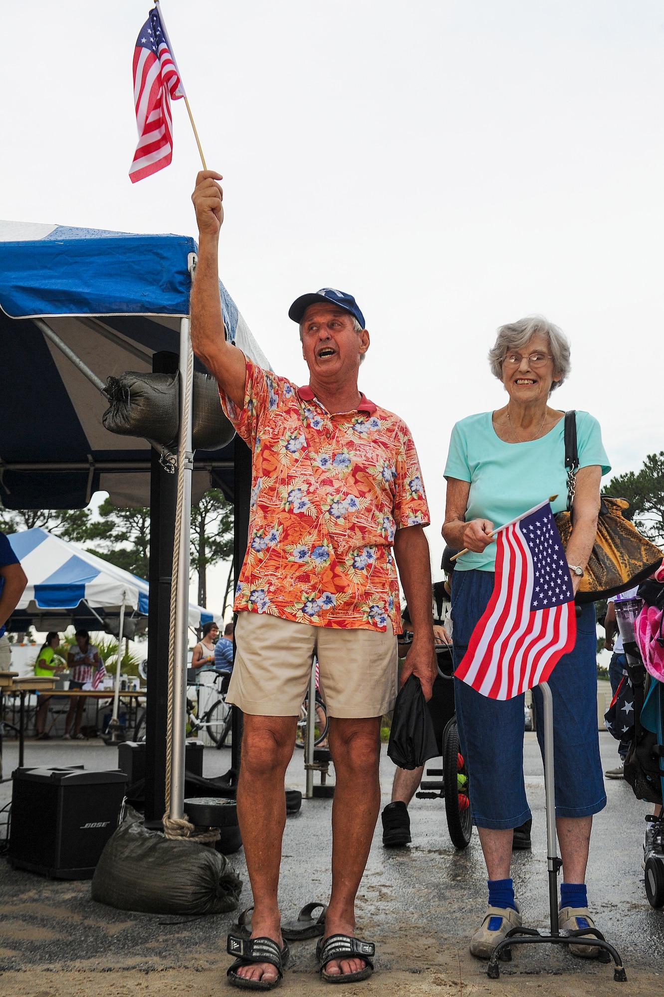 Retired Air Force Lt. Col. Paul Ozyck (left) and Mary Amyel, waive American flags during the cardboard boat regatta at the 18th Annual Sound of Independence at the Soundside Marina on Hurlburt Field, Fla., June 28, 2013. Squadrons from all across base worked in a number of different support positions to make sure everything’s ready to go so the military community could have an enjoyable experience. (U.S. Air Force photo/Airman 1st Class Christopher Callaway)