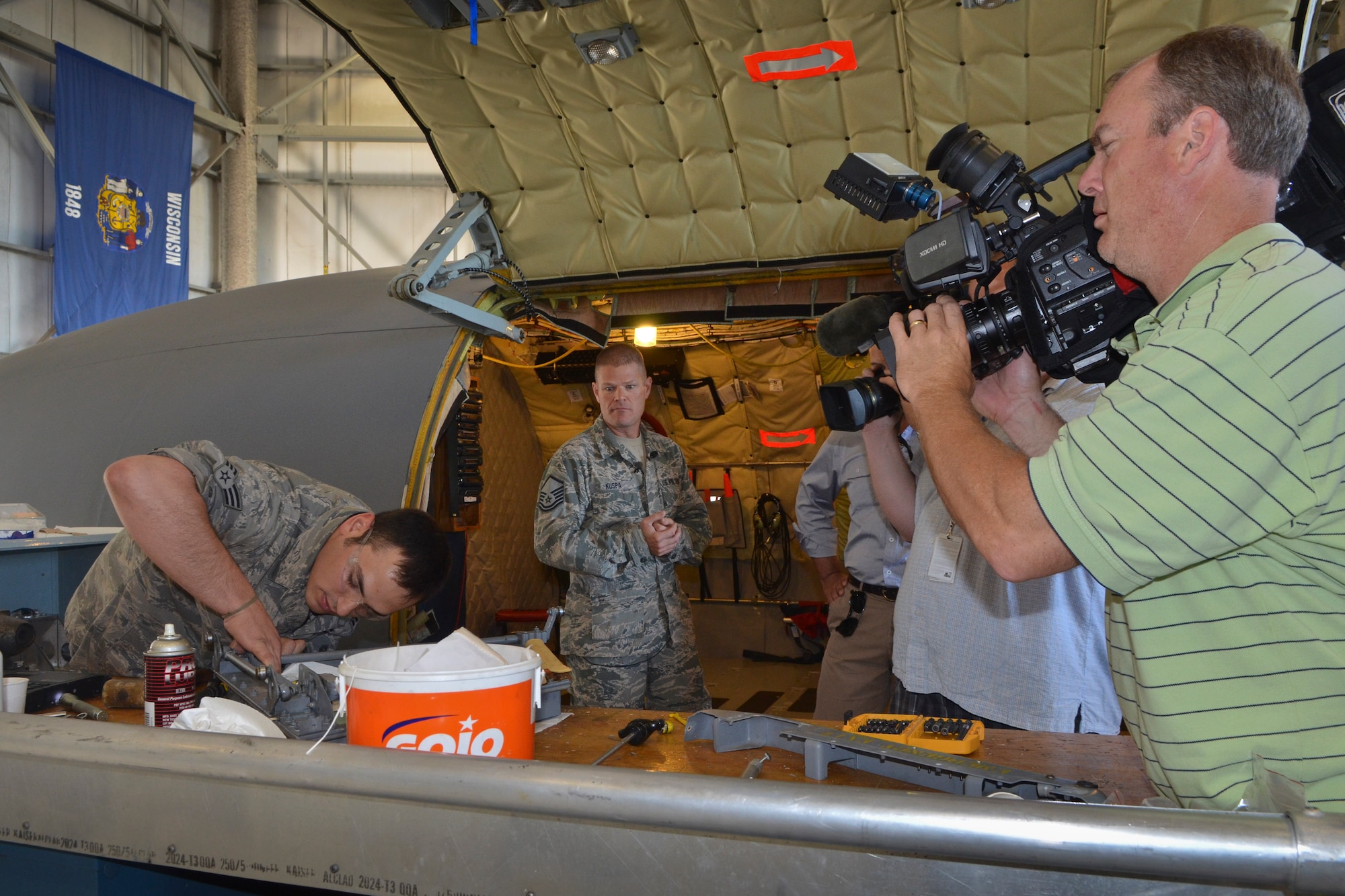 Television news crews from Milwaukee Wisconsin receive a tour of the isochronal inspection dock by Senior Master Sgt. Matthew Kuspa (center) at the 128th Air Refueling Wing, Wisconsin Air National Guard, June 28, 2013. The Milwaukee news teams were invited to attend a media engagement event at the air wing to learn more about the KC135R flight simulator and phase maintenance of the KC135R aircraft. (U.S. Air Force photo by Senior Master Sgt. Jeff Rohloff/Released)