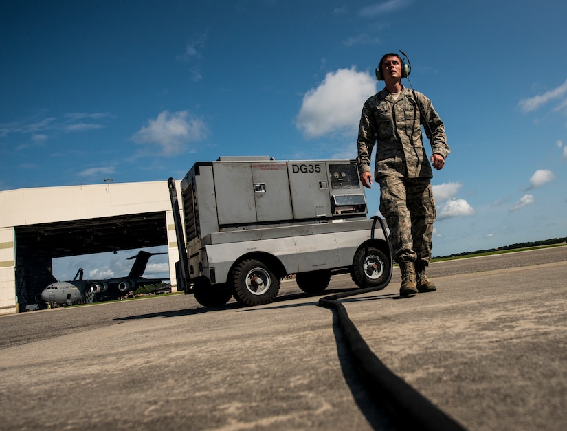 Senior Airman Clayton Valentine, 437th Maintenance Group jet-propulsion specialist, walks toward a C-17 Globemaster III after setting up a generator to be used during  a routine engine check June 26, 2013, at Joint Base Charleston – Air Base, S.C. Airmen from the 437th MXG perform routine maintenance to  C-17s daily. (U.S. Air Force photo/ Senior Airman Dennis Sloan)
