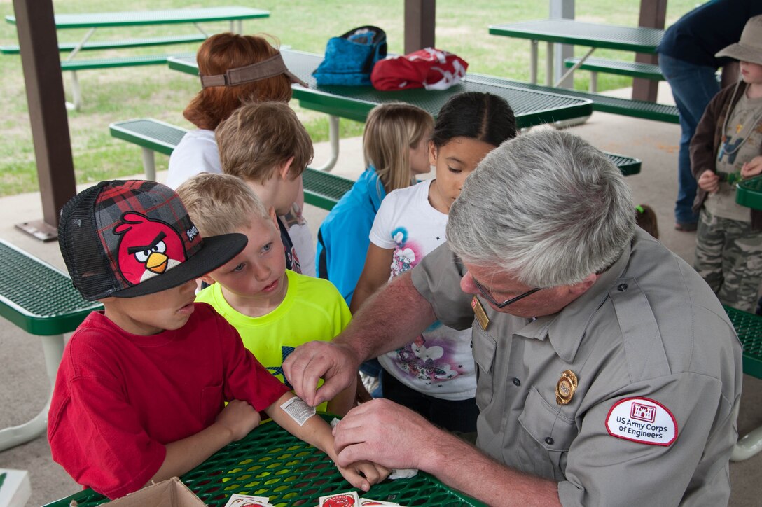 Rich Schueneman, site manager for Lake Ashtabula, near Valley City, N.D., gives temporary water
safety tattoos to a group of elementary students that helped plant trees at the park May 16.