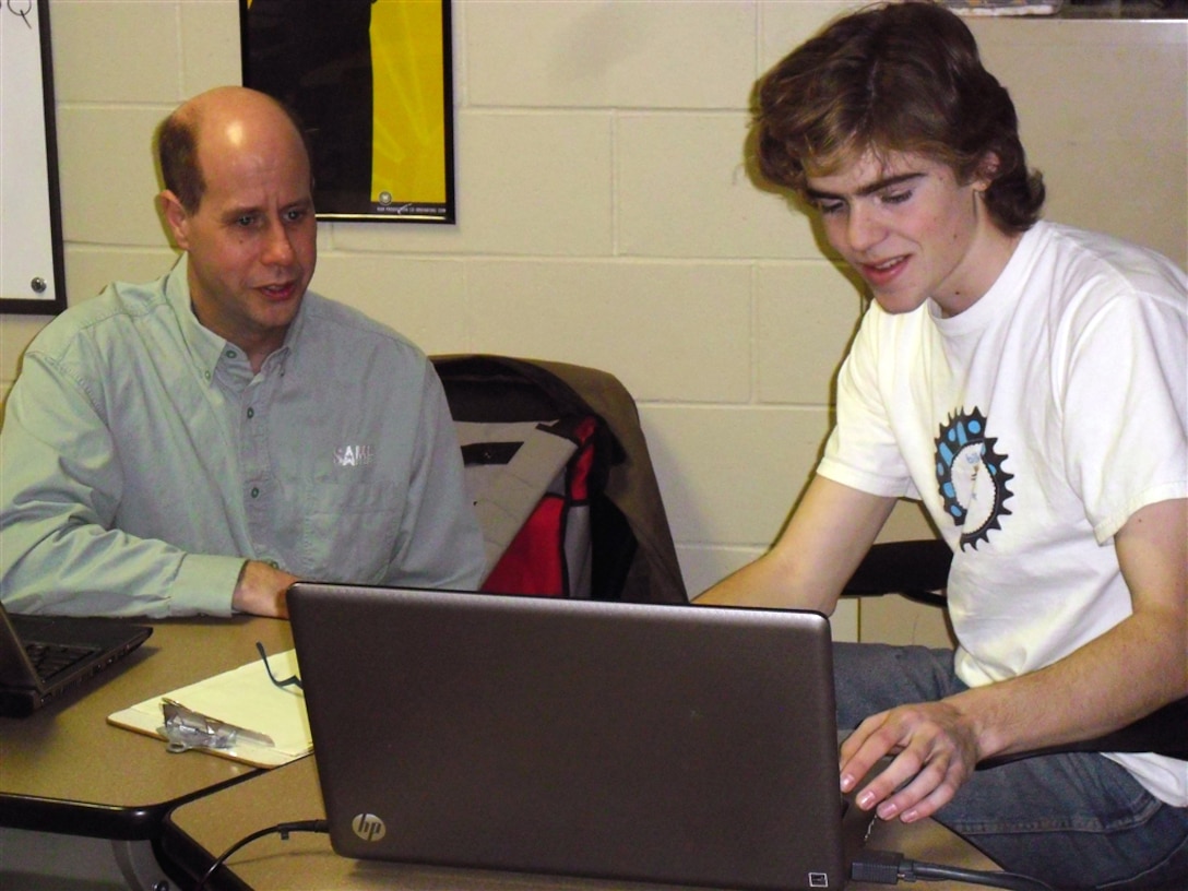 Rick Femrite, engineering and construction, discusses the robot computer aided design with Jacob Siekmeier, Fighting Calculators team member. The Fighting Calculators is a science, technology, engineering and mathematics team that participated in For Inspiration and Recognition of Science and Technology robotic competition.