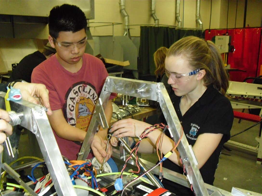 Teammates Greta Siekmeier and Mew Runggeratigul attaching a pneumatic cylinder to Trap, the Fighting Calculators robot. The Fighting Calculators is a science, technology, engineering and mathematics team that participated in For Inspiration and Recognition of Science and Technology robotic competition.