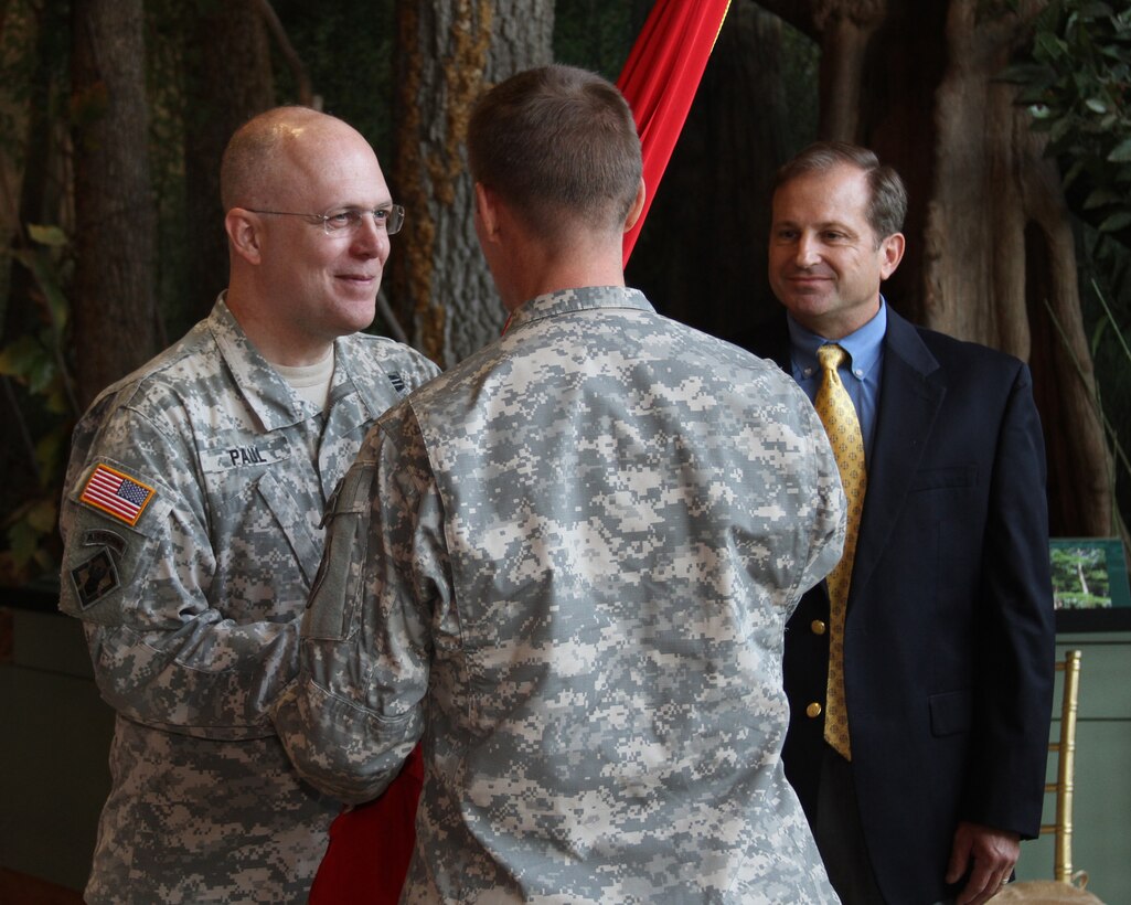 Col. Courtney Paul (left) accepts the Army Corps of Engineers flag, and with it command of the Corps’ Little Rock District, from Brig. Gen. Thomas Kula, the Corps’ Southwestern Division Commander, as Randy Hathaway, Little Rock District’s Deputy District Engineer (right) looks on during the district change of command ceremony.  The event was held July 2 at the Witt Stephens Jr. Central Arkansas Nature Center in downtown Little Rock.  (Photo courtesy of the Army Corps of Engineers)  