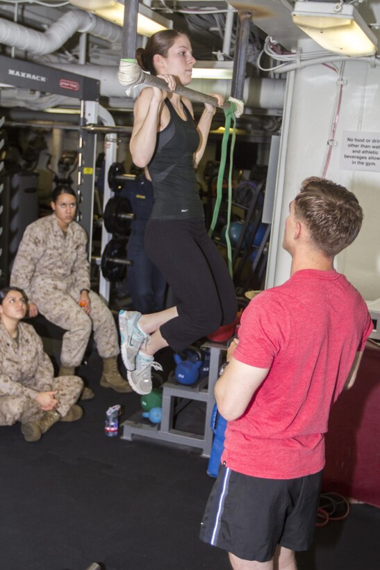 U.S. Marine Sgt. James Vincent, explosive ordnance disposal technician assigned to the 26th Marine Expeditionary Unit (MEU), explains the various muscle groups used while performing pull ups as Lance Cpl. Ashley Vallera, a signals intelligence analyst assigned to the 26th MEU, demonstrates the exercise during a period of professional military education in the gym of the USS Kearsarge, at sea, June 7, 2013.  The 26th MEU is a Marine Air-Ground Task Force forward-deployed to the U.S. 5th Fleet area of responsibility aboard the Kearsarge Amphibious Ready Group serving as a sea-based, expeditionary crisis response force capable of conducting amphibious operations across the full  range of military operations. (U.S. Marine Corps photo by Cpl. Kyle N. Runnels/Released)
