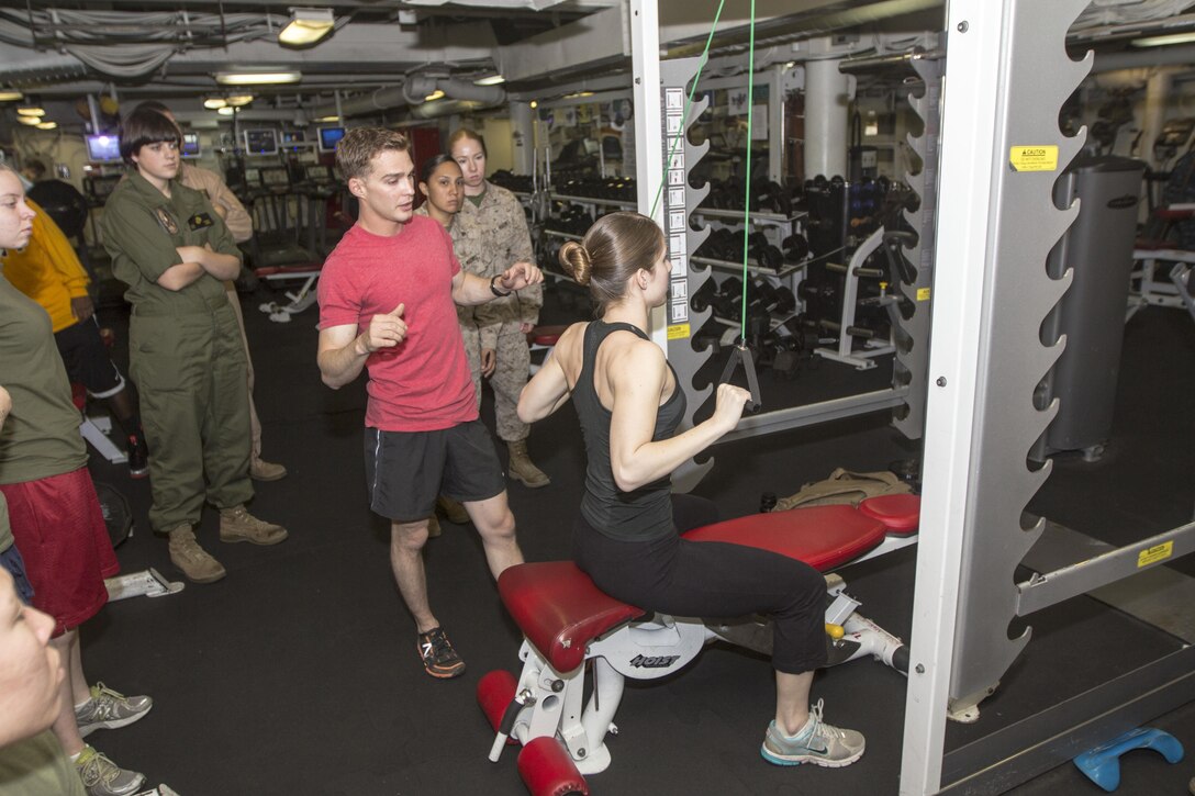 U.S. Marine Sgt. James Vincent, explosive ordnance disposal technician assigned to the 26th Marine Expeditionary Unit (MEU), explains the proper form for a seated row as Lance Cpl. Ashley Vallera, a signals intelligence analyst assigned to the 26th MEU, demonstrates the exercise during a period of professional military education in the gym of the USS Kearsarge, at sea, June 7, 2013.  The 26th MEU is a Marine Air-Ground Task Force forward-deployed to the U.S. 5th Fleet area of responsibility aboard the Kearsarge Amphibious Ready Group serving as a sea-based, expeditionary crisis response force capable of conducting amphibious operations across the full  range of military operations. (U.S. Marine Corps photo by Cpl. Kyle N. Runnels/Released)