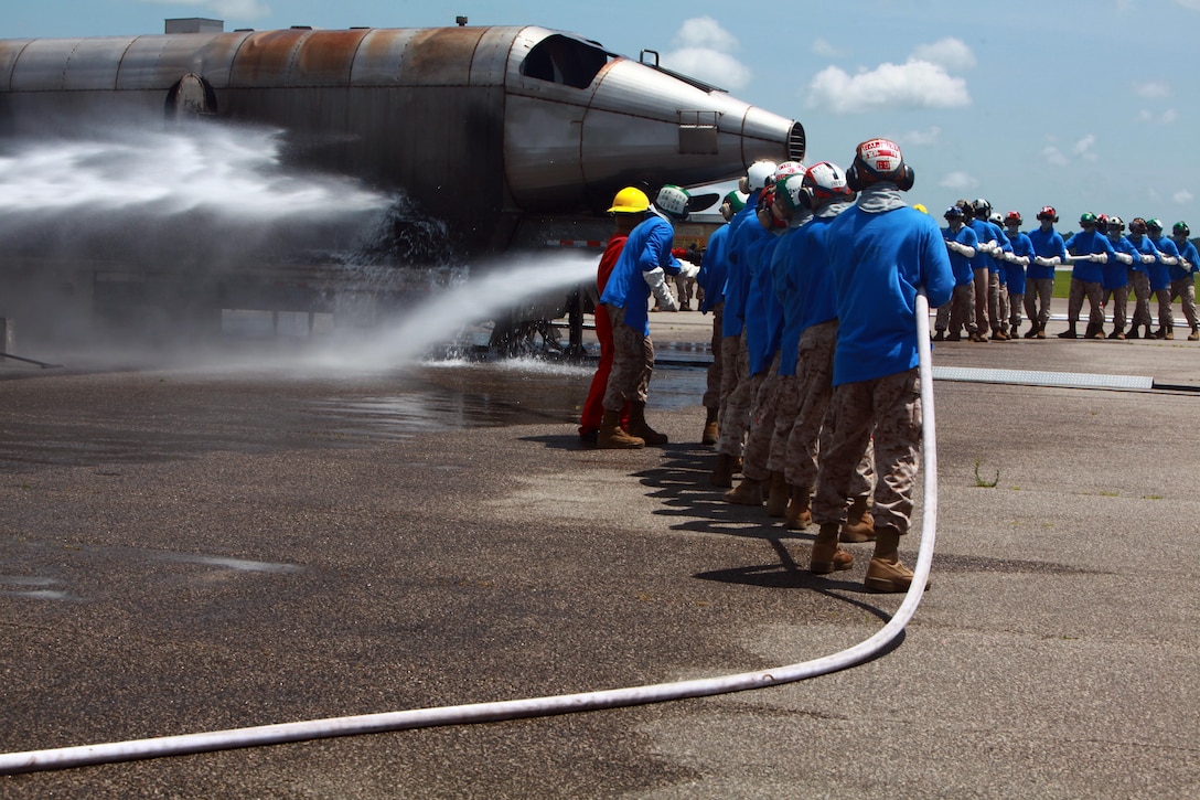 Marines from Marine Light Attack Helicopter Squadron 269 and Marine Medium Tiltroter Squadron 263 learn to use the fire hose on the Mobile Aircraft Firefighting Training Device during the shipboard training at Cherry Point June 26. The shipboard firefighting training is part of the required training for every Marine before they will be allowed to deploy on the 22nd Marine Expeditionary Unit.