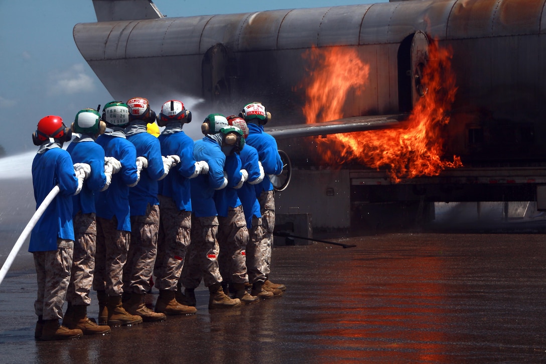 Marines from Marine Light Attack Helicopter Squadron 269 and Marine Medium Tiltroter Squadron 263 learn to use the fire hose on the Mobile Aircraft Firefighting Training Device during the shipboard training at Cherry Point June 26. The shipboard firefighting training is part of the required training for every Marine before they will be allowed to deploy on the 22nd Marine Expeditionary Unit.