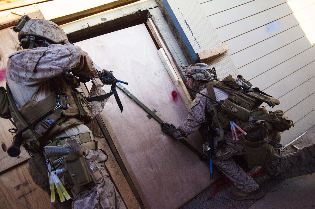 Staff Sgt. Brian Pittaway, 22nd Marine Expeditionary Unit force reconnaissance platoon team one team leader and native of Annapolis, Md., places a door breach while Staff Sgt. Andreas Owens, team one assistant team leader and native of Hendersonville, N.C., provides security during an assault on a live-fire house during close quarters combat training at Tier 1 Group in Crawfordsville, Ark., June 30, 2013. The Marines completed more than 200 hours of advanced pistol, rifle, sniper, tactical driving, breaching and close quarters combat training throughout the 18-day course. (Marine Corps photo by Sgt. Austin Hazard/released)