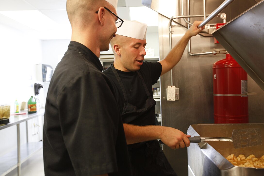 Lance Cpl. David Sullivan, a competitor in the Chef of the Quarter competition and food service specialist with H&HS, recieves pointers from Lance Cpl. Larry Meadows, Sullivan’s mentor and a food service specialist with H&HS, during the Chef of the Quarter competition June 27. 