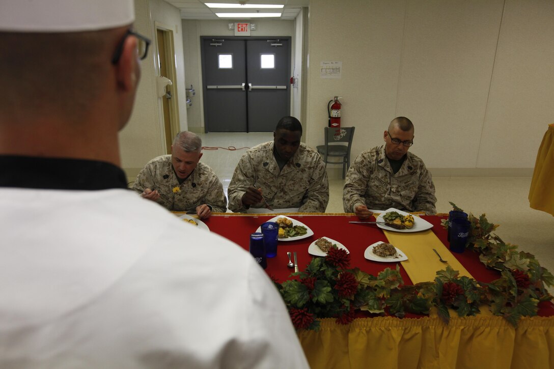 Lance Cpl. David Sullivan, a competitor in the Chef of the Quarter competition and food service specialist with H&HS, watches as judges Sgt. Maj. David Eldridge, Headquarters and Headquarters Squadron sergeant major, Sgt. Maj. Darrell D. Rowe, the Marine Wing Support Squadron 274 sergeant major, and Sgt. Maj. Douglas Schaefer, sergeant major of Marine Wing Support Squadron 271, eat his steak and shrimp dish June 27. 