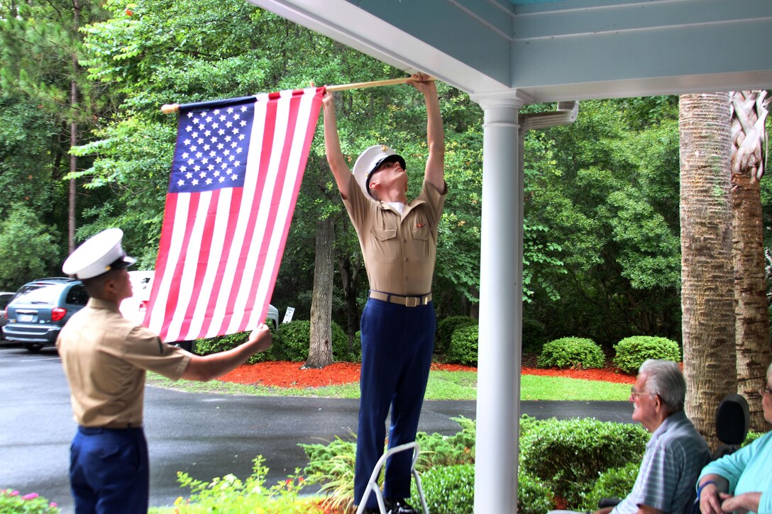 Lance Cpl. John-Paul Imbody, photo specialist with the 6th Marine Corps District, and Private First Class Stanley Cao, combat correspondent also with the 6MCD, post the American flag at the Bloom at Bluffton Home Care Center for the elderly in Bluffton, S.C., July 2, 2013.   Marines from the 6MCD and MCRD Parris Island volunteered to post the flag at the care center, spending quality time with its residents in spirit of the upcoming 4th of July holiday.