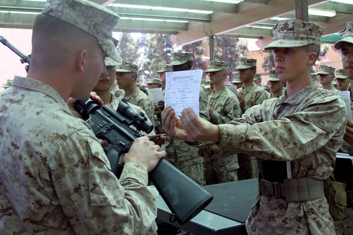 An armorer confirms the M-16 A-4 service rifle serial number matches the one on the information card before handing it to a recruit from Company D, 1st Recruit Training Battalion, aboard Marine Corps Recruit Depot San Diego June 17.  