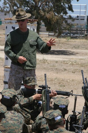 Cpl. Justin L. Newman, Primary Marksmanship Instructor, Weapons and Field Training Battalion, shows recruits how to get in a proper sitting shooting position during Grass Week at Edson Range aboard Marine Corps Base Camp Pendleton, Calif. June 25.  The primary marksmanship instructors ensure recruits are well trained in the shooting techniques and positions to make sure recruits perform well during their shooting range qualification.