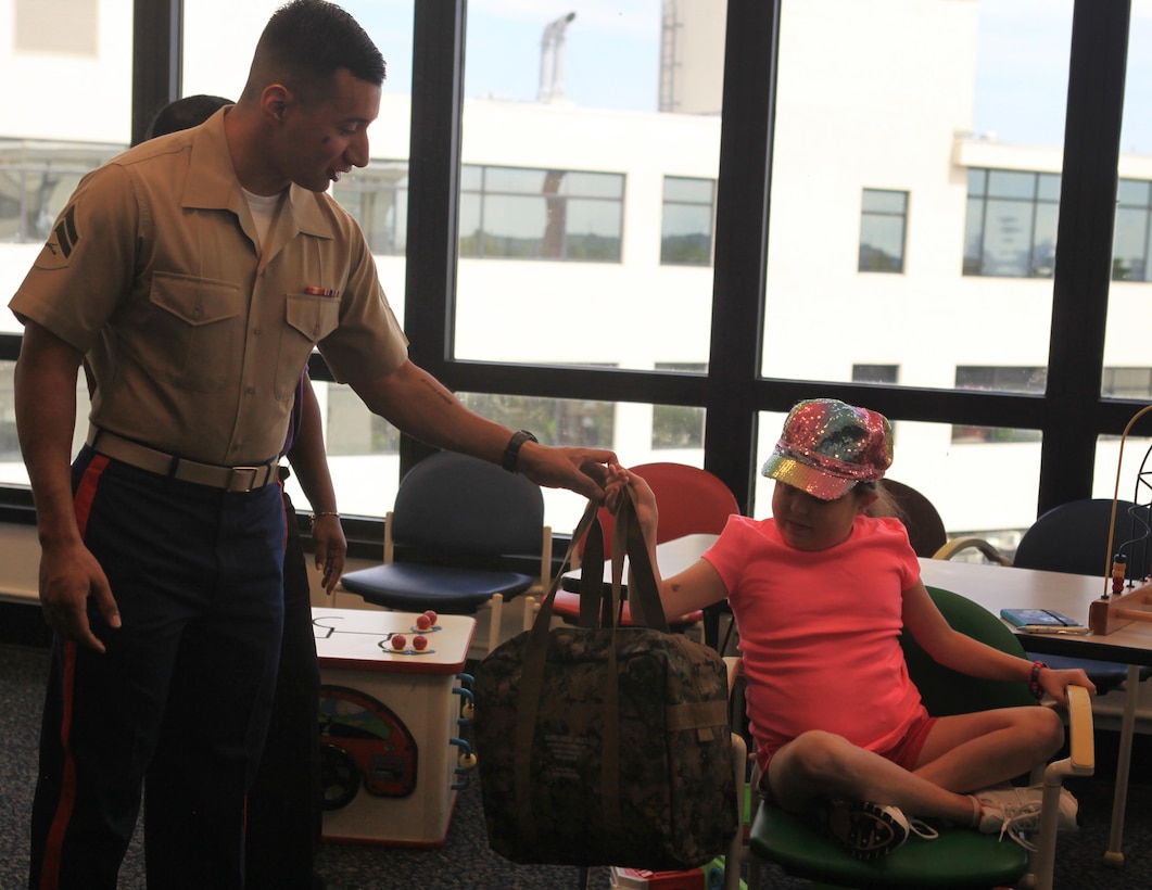 NEW ORLEANS – Cpl. Edgar Vazquez, a finance administration specialist with Marine Forces Reserve, hands Gabrielle Hidalgo, 13, a gift bag during a trip to Children’s Hospital New Orleans, July 3. Marine volunteers from the MARFORRES command deck and finance department brought donated gifts to the hospital and visited with patients, parents and doctors, in an effort to boost morale and cultivate strong community ties. (U.S. Marine Corps photo by Lance Cpl. Tiffany Edwards)