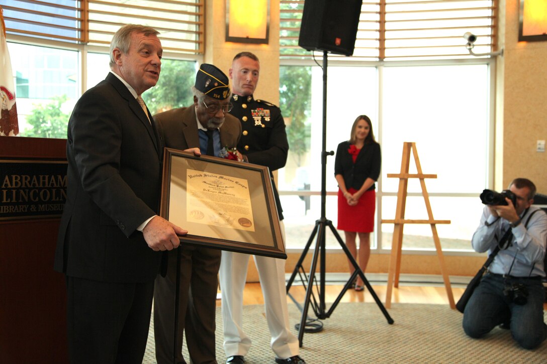 Sen. Dick Durbin and Maj. Gegory Gordon present Cpl. (ret) Deloyce McMurray with Congressional Gold Medal during a Montford Point Marine ceremony July 2 at the Abraham Lincoln Presidential Library. McMurray enlisted in the Marine Corps in 1944 and was one of the few African Americans sent to the segregated Montford Point, North Carolina for basic training. McMurray was deployed to the Pacific during World War II seeing action during the battle of Iwo Jima. (U.S. Marine Corps photo by Cpl. Erik S. Brooks Jr./ Released)