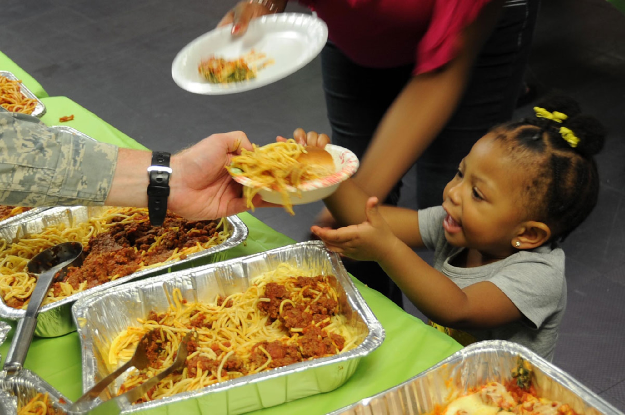 Nevaeh Clark receives food from volunteers while the Deployed Spouses Dinner June 27. The dinner was a way for spouses to connect with one another and with unit personnel while their loved ones are deployed around the world.