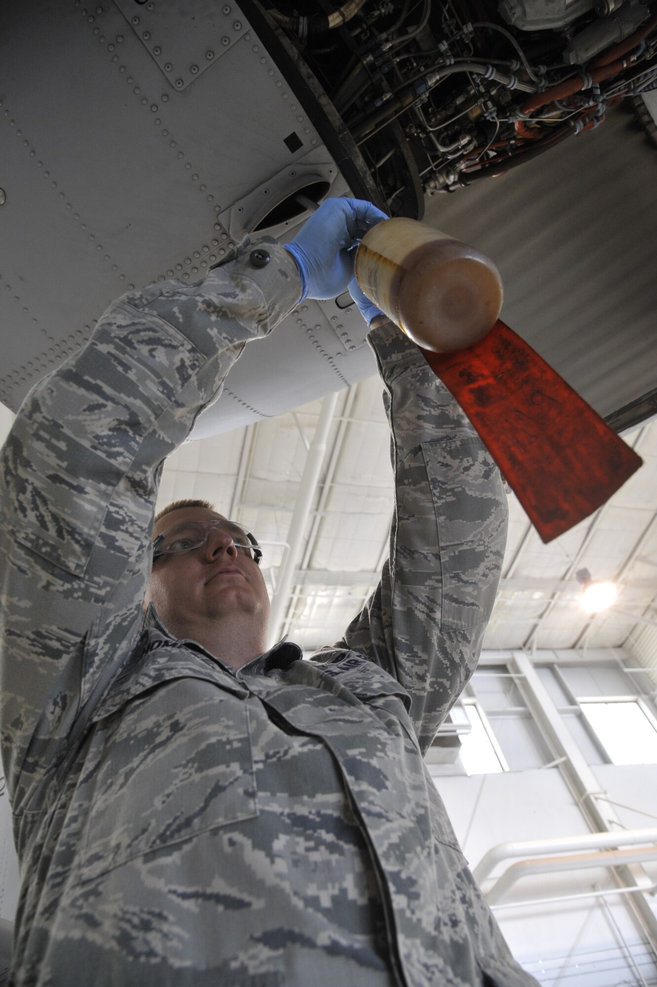 Tech. Sgt. Brandon Thompson, 442nd Maintenance Squadron phase dock coordinator, installs a fuel- catch bottle on an engine of an A-10 Thunderbolt II at Whiteman Air Force Base, Mo., June 11, 2013. This bottle is designed to catch fuel dripping from an engine, which could cause slip hazards and various pollution concerns. (U.S. Air Force photo by Airman 1st Class Keenan Berry/Released)	